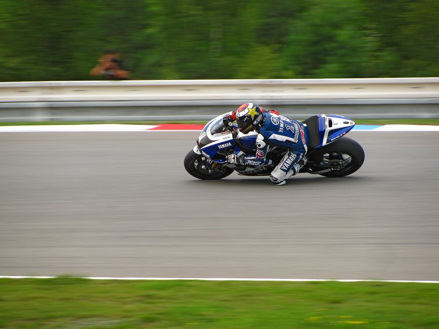 Podium celebration with close-up of riders, tire marks visible, speed blur effect